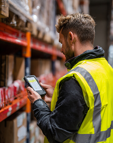 worker in warehouse looking at app on smartphone